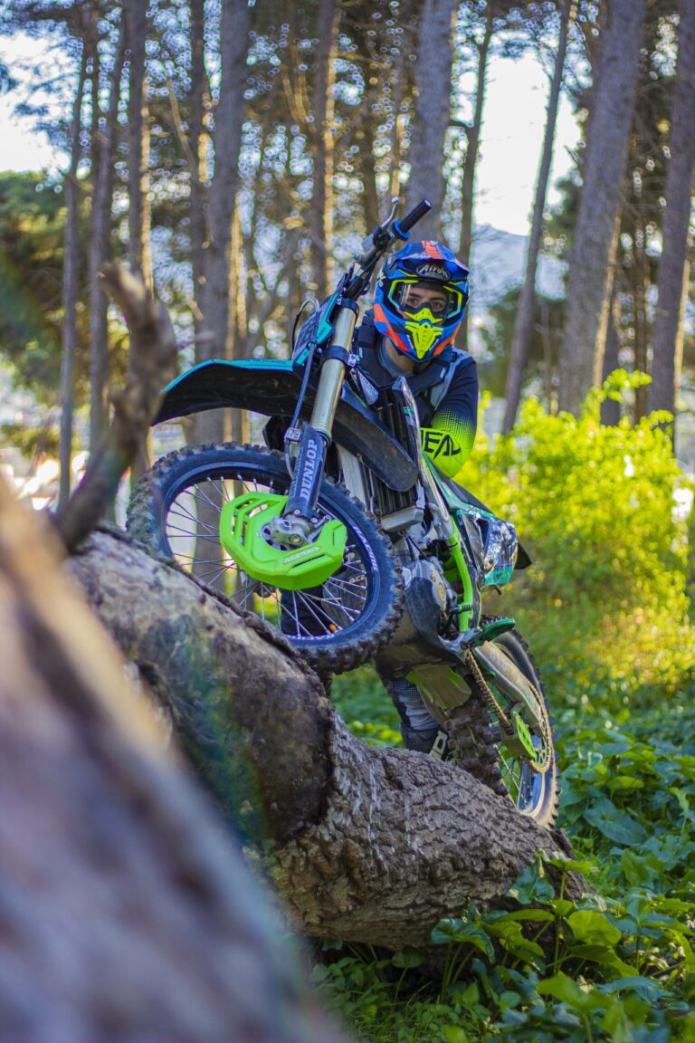 Dirt bike rider crossing a fallen tree on the trail