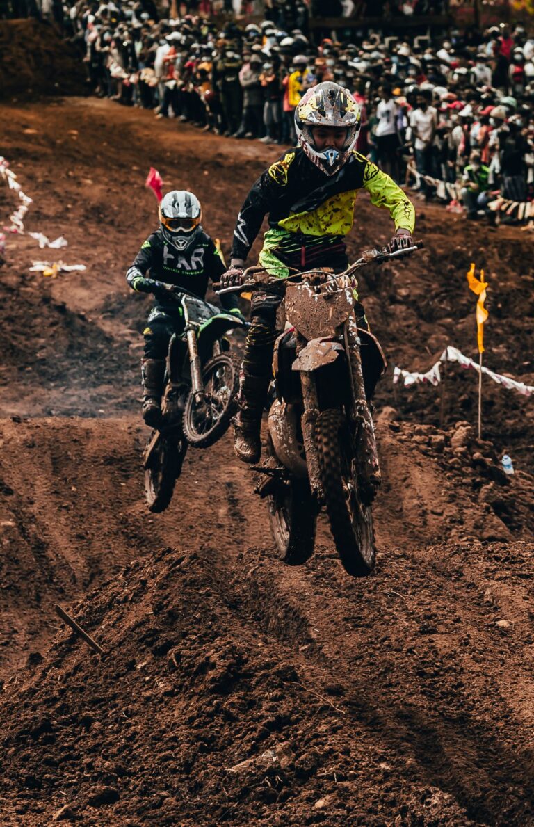 Two motocross riders racing on a muddy track