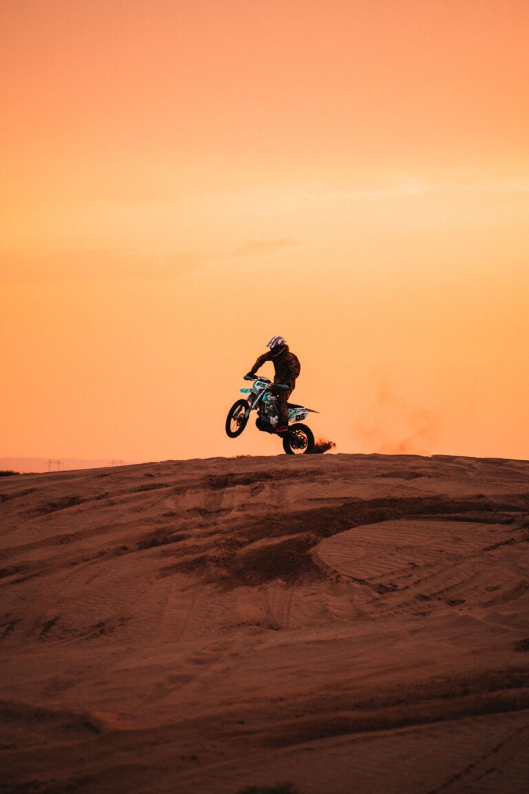 Lone rider crossing desert dunes at sunset