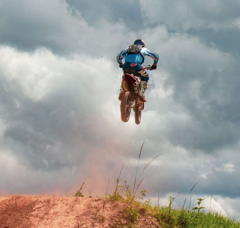 Dirt bike soaring under dramatic clouds